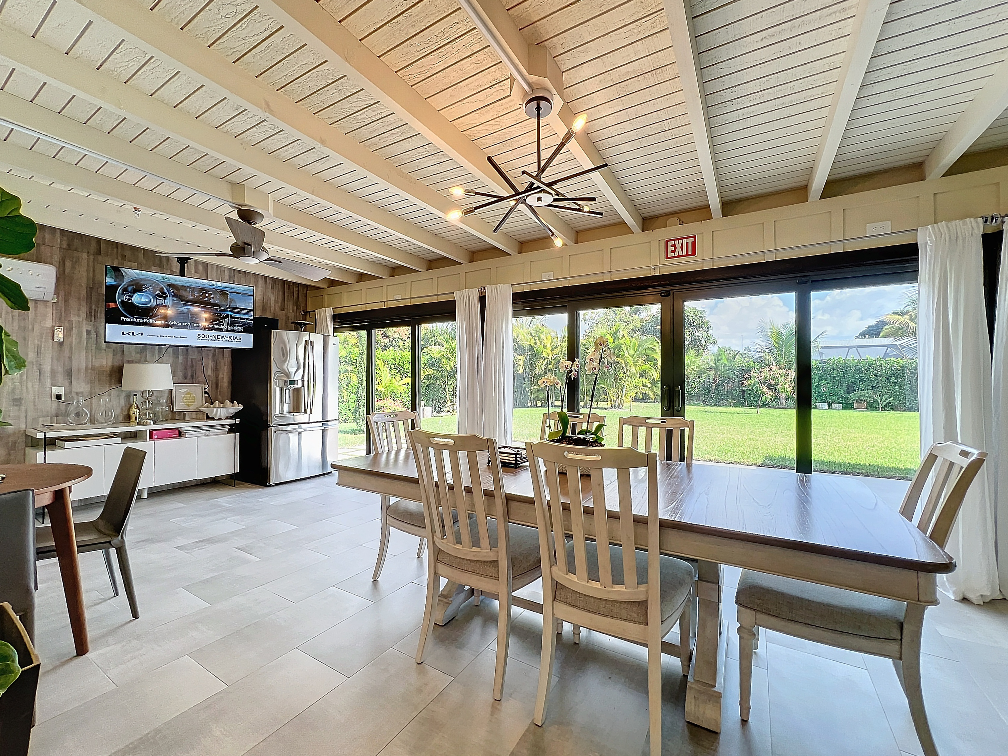 Bright sunroom space set up with dining furniture and recreation amenities at Abundant Care Residence in Wellington, FL